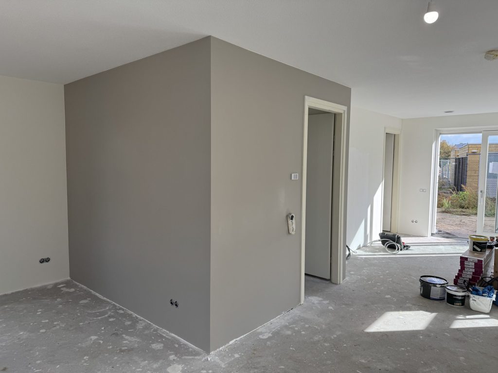 Pas gesausde wand in een warme grijstint in een woning die nog wordt afgewerkt